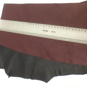 May include: A piece of burgundy leather with a black leather border. A ruler with the text "JAKAR 7379" is placed on top of the leather.