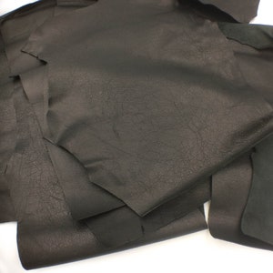 Könnte beinhalten: Ein Stapel schwarzer Lederstücke, die die Textur des Materials zeigen.