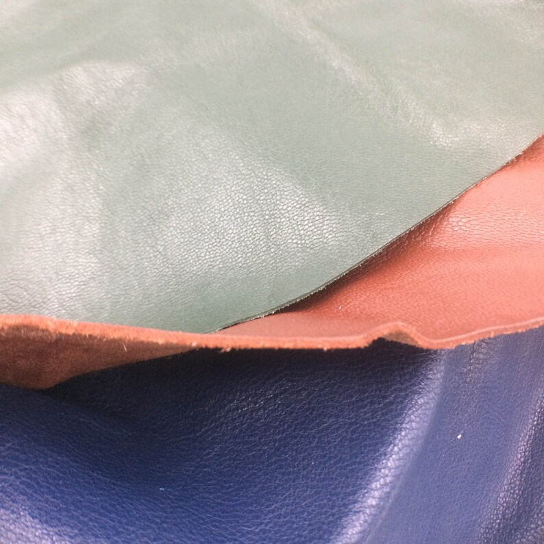 May include: Three pieces of leather in different colors: green, brown, and blue. The leather is textured and has a natural look.