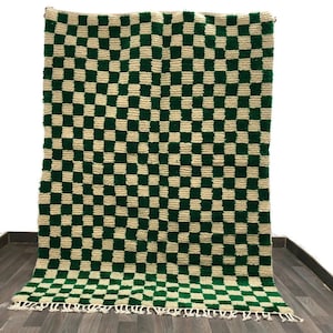 May include: A green and cream checkered rug with fringe on the edges. The rug is made of a soft, fluffy material.