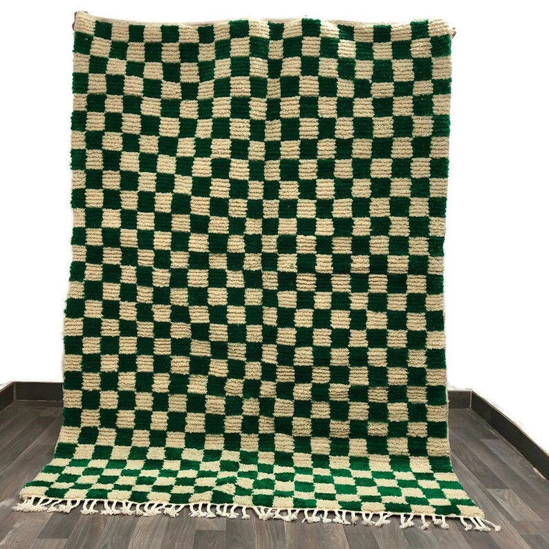 May include: A green and cream checkered rug with fringe on the edges. The rug is made of a soft, fluffy material.