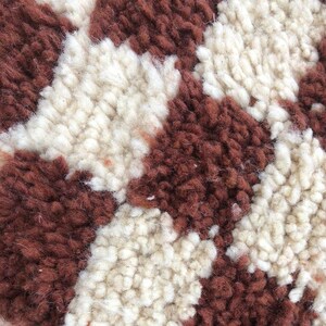 Peut inclure: Gros plan sur un tapis moelleux brun et blanc &agrave; motif &agrave; carreaux.