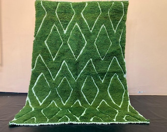 May include: A green and white Moroccan rug with a diamond pattern. The rug has a fringe border.