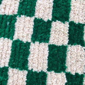 Peut inclure: Gros plan d'un tapis &agrave; carreaux avec des carr&eacute;s altern&eacute;s de tissu vert et cr&egrave;me. Le tapis est fait d'un mat&eacute;riau doux et moelleux.