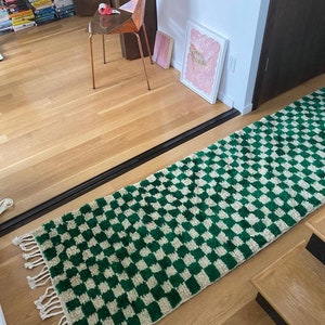 Peut inclure: Un tapis &agrave; carreaux verts et blancs avec des franges aux extr&eacute;mit&eacute;s. Le tapis est pos&eacute; sur un sol en bois dans un couloir.