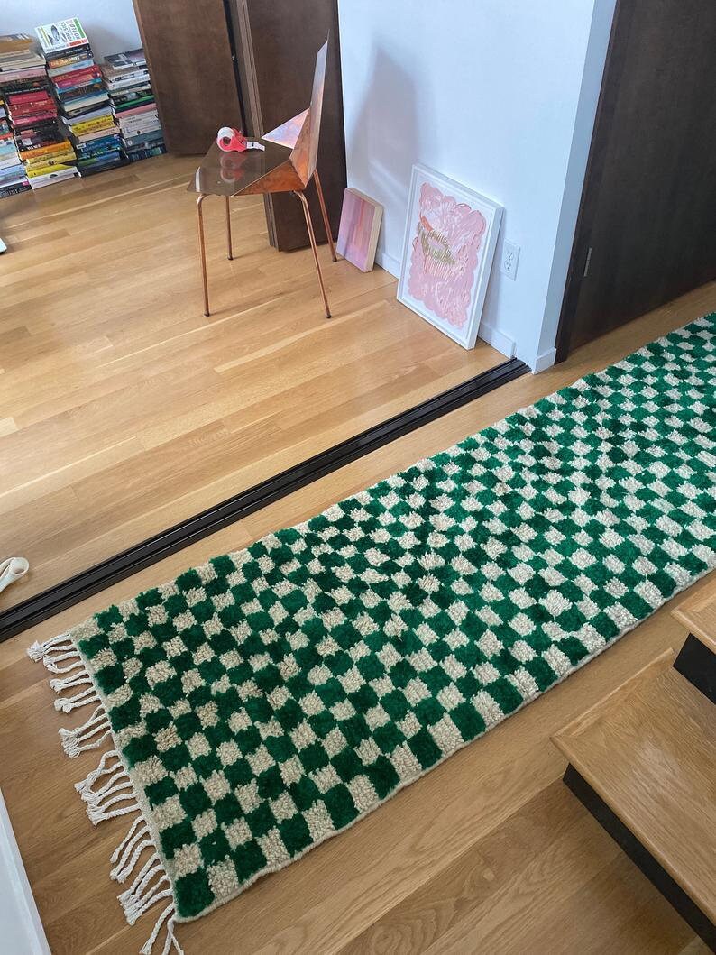 Peut inclure: Un tapis &agrave; carreaux verts et blancs avec des franges aux extr&eacute;mit&eacute;s. Le tapis est pos&eacute; sur un sol en bois dans un couloir.