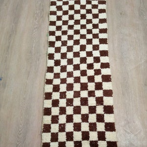 Peut inclure: Un tapis rectangulaire long avec un motif &agrave; carreaux en brun et blanc. Le tapis est fait d'un mat&eacute;riau doux et moelleux.