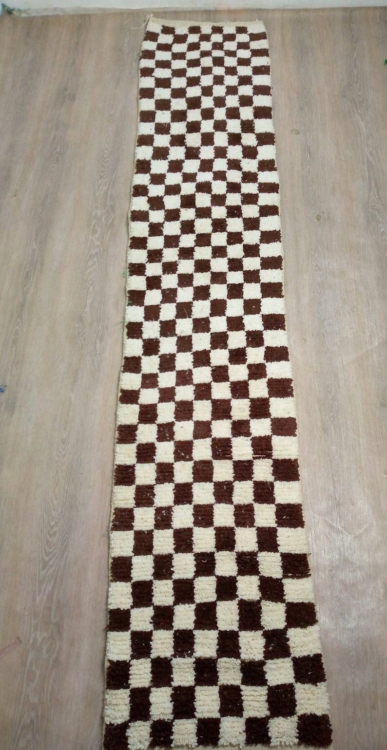 Peut inclure: Un tapis rectangulaire long avec un motif &agrave; carreaux en brun et blanc. Le tapis est fait d'un mat&eacute;riau doux et moelleux.