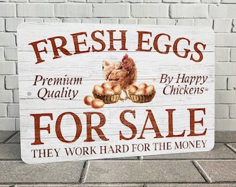 May include: White wooden sign with red text that reads "FRESH EGGS Premium Quality By Happy Chickens FOR SALE THEY WORK HARD FOR THE MONEY". A brown hen and a basket of eggs are pictured on the sign.