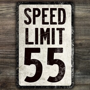 May include: A vintage-style speed limit sign with a white background and black lettering. The sign reads "SPEED LIMIT 55".