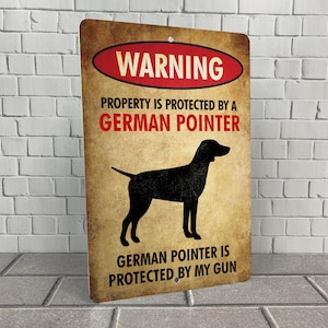 May include: A warning sign with a brown background and red text that reads "WARNING". The sign also features a black silhouette of a German Shorthaired Pointer dog and the text "PROPERTY IS PROTECTED BY A GERMAN POINTER GERMAN POINTER IS PROTECTED BY MY GUN".