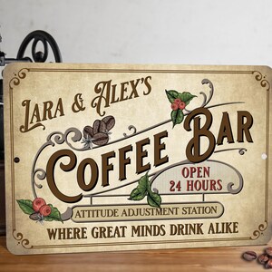 May include: A vintage-style metal sign with a brown background and white text. The sign reads "Lara & Alex's Coffee Bar, Open 24 Hours, Attitude Adjustment Station, Where Great Minds Drink Alike".