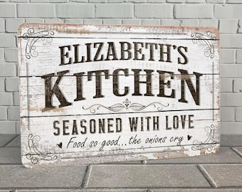 May include: White wooden sign with black text that reads "Elizabeth's Kitchen Seasoned with Love Food so good... the onions cry".