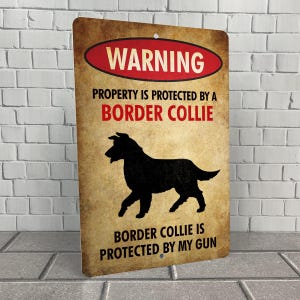 May include: A warning sign with a rustic brown background and red text. The sign reads "WARNING PROPERTY IS PROTECTED BY A BORDER COLLIE BORDER COLLIE IS PROTECTED BY MY GUN". A black silhouette of a Border Collie dog is in the center of the sign.