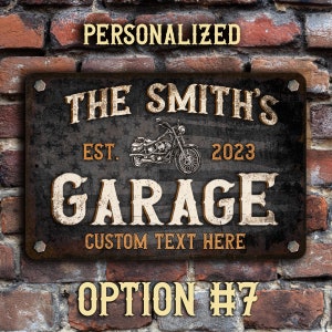 May include: Personalized metal sign with a distressed black background and white lettering. The sign reads "The Smith's Garage Est. 2023 Custom Text Here". A vintage motorcycle illustration is featured in the center of the sign.