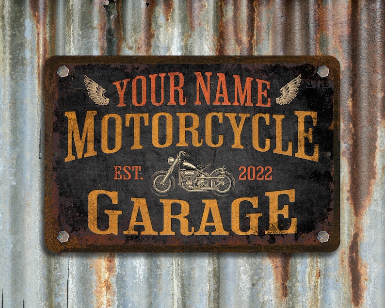 Pu&ograve; includere: Segno in metallo rustico con una silhouette di una motocicletta, il testo "YOUR NAME MOTORCYCLE GARAGE EST. 2022" e ali decorative.