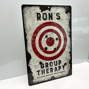 May include: A vintage-style metal sign with a red and white target and the text "Ron's Group Therapy Building Healthy Relationships".