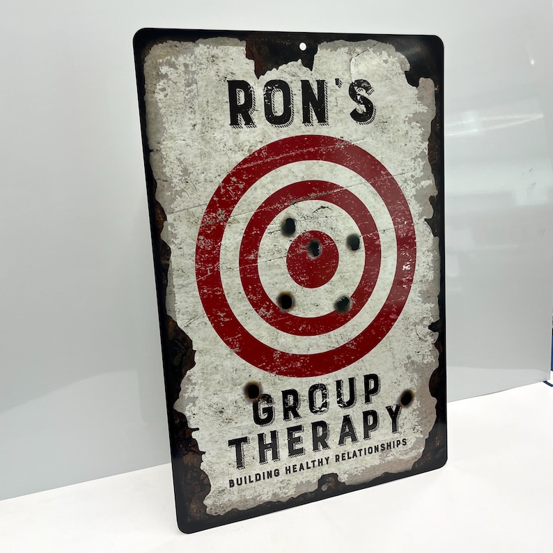 May include: A vintage-style metal sign with a red and white target and the text "Ron's Group Therapy Building Healthy Relationships".