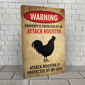 May include: A warning sign with a distressed, vintage look. It features a black silhouette of a rooster with the text "WARNING PROPERTY IS PROTECTED BY AN ATTACK ROOSTER ATTACK ROOSTER IS PROTECTED BY MY GUN".