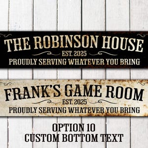 May include: Two black and white metal signs with distressed paint. The top sign reads "The Robinson House Est. 2025 Proudly Serving Whatever You Bring". The bottom sign reads "Frank's Game Room Est. 2025 Proudly Serving Whatever You Bring".