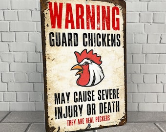 Op de afbeelding: Een waarschuwingsbord met een rode haan-illustratie en de tekst "Warning Guard Chickens May Cause Severe Injury or Death They Are Real Peckers Made in the USA".