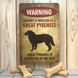 Puede incluir: Un cartel de advertencia con un aspecto desgastado y vintage. El cartel es marr&oacute;n con texto rojo y blanco. Dice "WARNING PROPERTY IS PROTECTED BY A GREAT PYRENEES GREAT PYRENEES IS PROTECTED BY MY GUN". Una silueta negra de un perro de monta&ntilde;a de los Pirineos est&aacute; en el centro del cartel.
