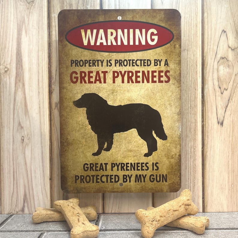 Puede incluir: Un cartel de advertencia con un aspecto desgastado y vintage. El cartel es marr&oacute;n con texto rojo y blanco. Dice "WARNING PROPERTY IS PROTECTED BY A GREAT PYRENEES GREAT PYRENEES IS PROTECTED BY MY GUN". Una silueta negra de un perro de monta&ntilde;a de los Pirineos est&aacute; en el centro del cartel.