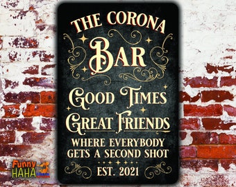 May include: Black metal sign with the words "THE CORONA BAR" in a decorative font. The sign also reads "GOOD TIMES GREAT FRIENDS" and "WHERE EVERYBODY GETS A SECOND SHOT EST. 2021". The sign is against a brick wall.