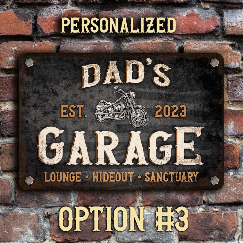 May include: A black metal sign with a distressed finish featuring the text "Dad's Garage Est. 2023 Lounge Hideout Sanctuary" with a motorcycle graphic.