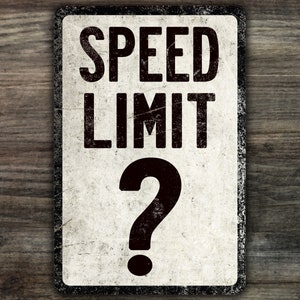 May include: A white, weathered metal sign with black text that reads "SPEED LIMIT" and a large black question mark. The sign has a distressed, vintage look.