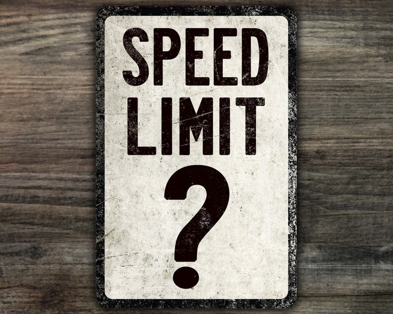 May include: A white, weathered metal sign with black text that reads "SPEED LIMIT" and a large black question mark. The sign has a distressed, vintage look.