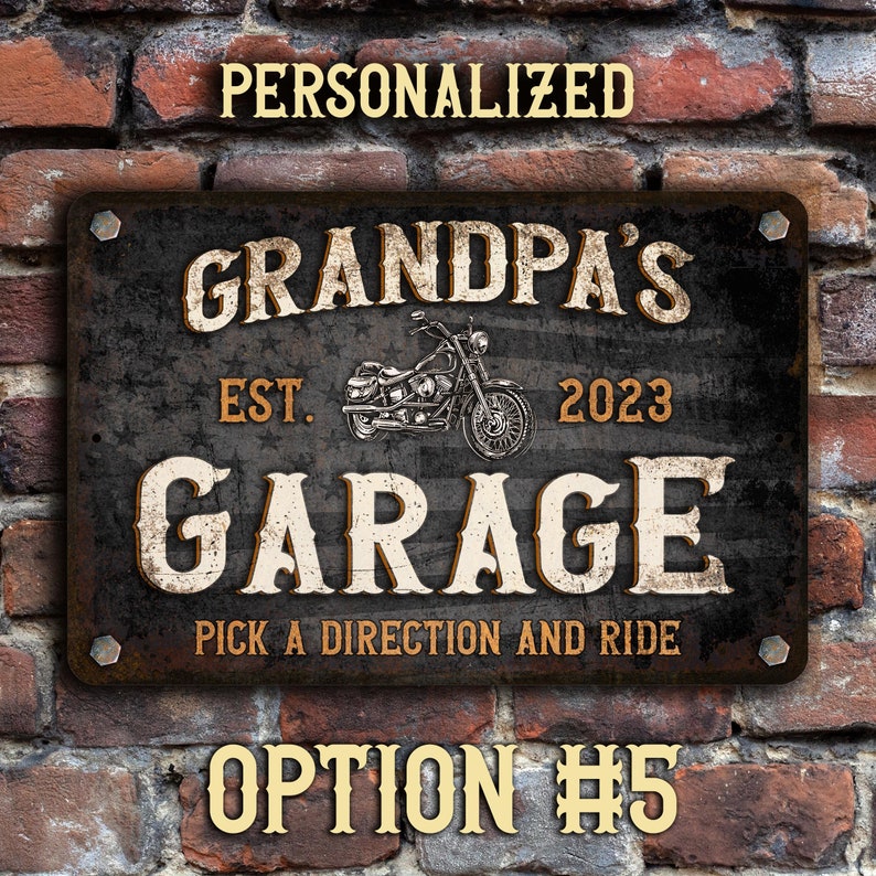 May include: A black metal sign with a distressed finish. The sign reads "Grandpa's Garage Est. 2023 Pick a Direction and Ride". A motorcycle is pictured in the center of the sign.