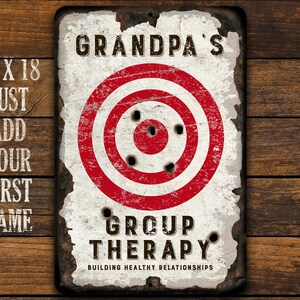 May include: A white metal sign with a red and white target in the center. The sign says "Grandpa's Group Therapy Building Healthy Relationships".