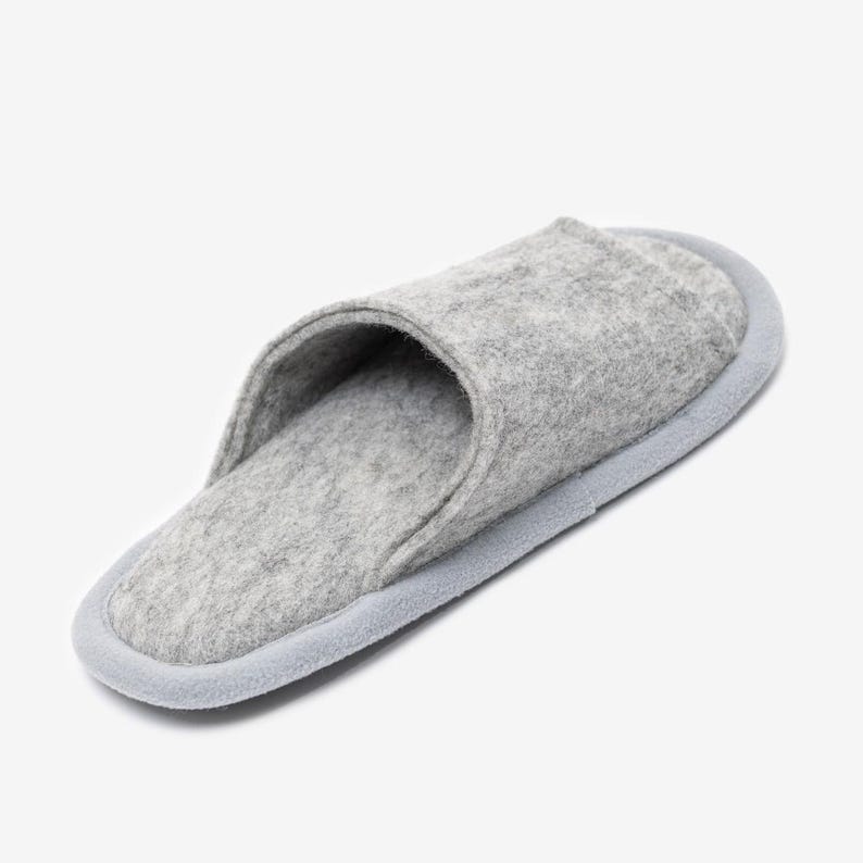 Peut inclure: Une paire de pantoufles en feutre gris avec une bordure gris clair autour des bords. Les pantoufles sont faites d'un mat&eacute;riau doux et confortable et ont un design simple et minimaliste.