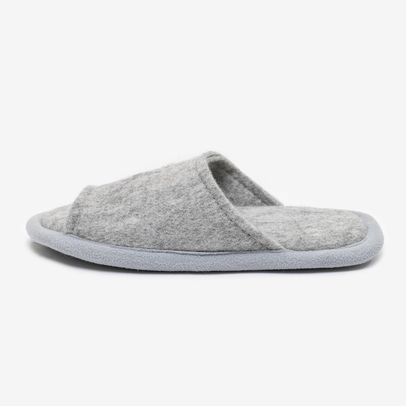 Peut inclure: Chaussons d'int&eacute;rieur en feutre gris avec un bout ferm&eacute; et un dos ouvert. Les chaussons ont une semelle gris clair.