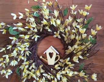 May include: A yellow wreath made of twigs and yellow flowers with a small yellow birdhouse in the center.