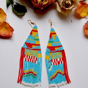May include: A pair of long, beaded earrings with a geometric pattern in red, yellow, blue, green, and white. The earrings have a fringe of beads at the bottom.