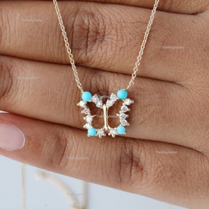 May include: A gold butterfly pendant necklace with turquoise stones and diamonds. The necklace is on a delicate chain.
