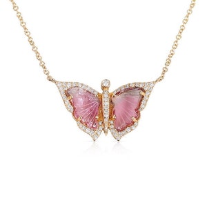 May include: A delicate gold chain necklace featuring a pink butterfly pendant. The butterfly is carved from a pink gemstone and has a diamond halo around it.