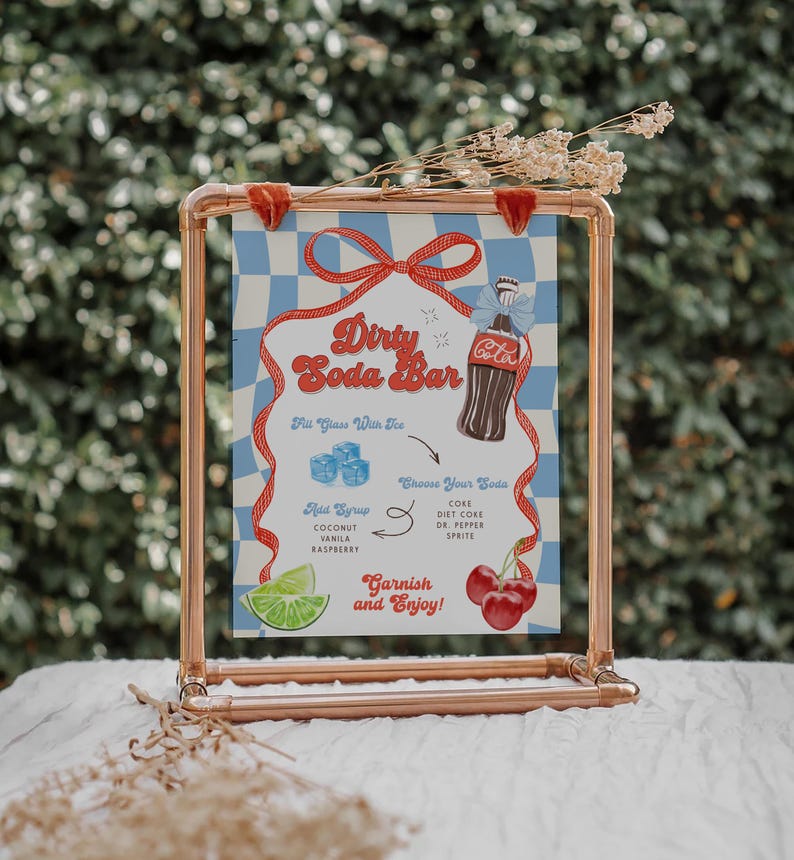 May include: A copper-colored metal frame holds a sign with a blue and white checkered background. The sign reads "Dirty Soda Bar" with illustrations of a soda bottle, ice cubes, and garnishes. The sign includes text for soda flavors and garnishes.