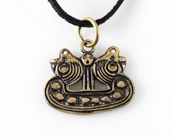 May include: A gold-toned pendant necklace with a detailed design of two stylized birds facing each other. The pendant is attached to a black leather cord.