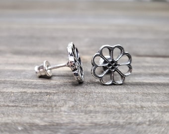 May include: A pair of silver flower-shaped stud earrings. The earrings have a delicate, openwork design.