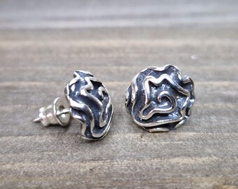 May include: A pair of silver stud earrings with a textured, swirling design. The earrings are round and have a post back.