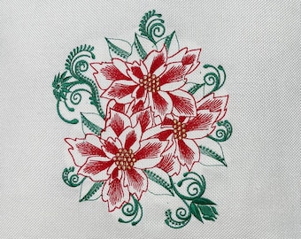 Puede incluir: Almohada blanca con un diseño floral bordado en rojo y verde. El diseño presenta tres flores de poinsettia con hojas y tallos verdes.