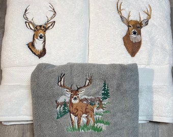 May include: Three towels with embroidered deer designs. One towel is gray with a deer standing in a forest scene and the name "Joe" embroidered below. The other two towels are white with a deer head design.