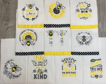 May include: Set of 10 white kitchen towels with black and yellow polka dot trim. Each towel features an embroidered bee design with a bee-themed saying. The sayings include: "Honey Bee Mine", "Let it Bee", "Don't Forget to Bee Awesome", "Life is Sweet When You Are Kind", "Welcome to Our Hive the Best Place to Bee", "Ever Busy Bees Stop and Smell the Roses", "Mind Your Own Beeswax".