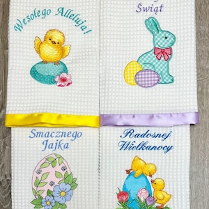 May include: Four white kitchen towels with embroidered Easter designs. The top left towel features a yellow chick on a blue egg with the text "Wesołego Alleluja!" The top right towel features a blue bunny with a pink bow holding a yellow and purple egg with the text "Wesołych Świąt". The bottom left towel features a pink egg with green leaves and blue flowers with the text "Smacznego Jajka". The bottom right towel features two yellow chicks on a blue egg with the text "Radosnej Wielkanocy".