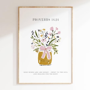 May include: A framed wall art print featuring the text PROVERBS 16:24 at the top and KIND WORDS ARE LIKE HONEY - SWEET TO THE SOUL AND HEALING FOR THE BODY at the bottom. A watercolour illustration shows a jar of honey with a pink bow and flowers.