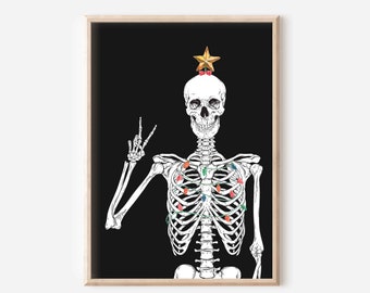 Op de afbeelding: Een ingelijste kunstdruk met een skelet tegen een zwarte achtergrond, versierd met kerstverlichting en een gouden ster. Het skelet maakt het vredesteken. Het kunstwerk zit in een houten lijst.