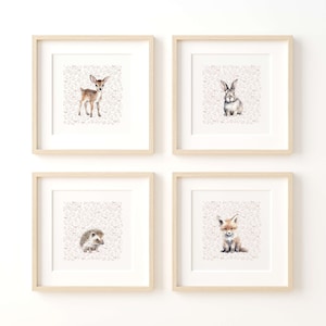 May include: Four framed prints with a white background and a pink floral pattern. Each print features a different woodland animal: a deer, a rabbit, a hedgehog, and a fox.